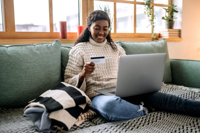Person-sitting-on-couch-at-home-using-laptop-while-holding-credit-card_-Pekic.jpg