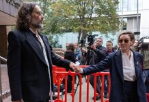 Russell Brand and wife Laura hold hands as they leave his sexual assault trial in London