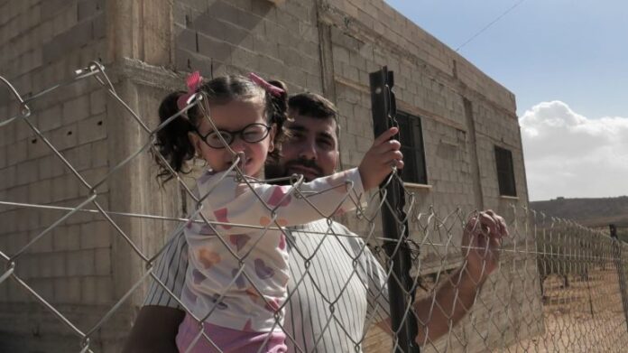 Abd-Al-rahman-Jaber-stands-with-his-daughter-near-the-iron-fence-he-erected-around-his-house-to-protect-it-from-settlers-attacks-Photo-by-Motasem-Abu-Alia-1792329879.jpg